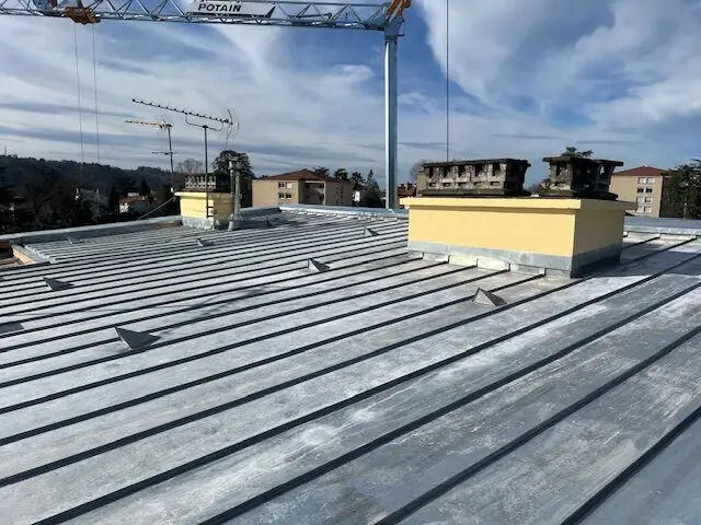 Avant / Après - Remplacement d’une couverture en amiante par une couverture en zinc à joint debout 1 Remplacement d’une couverture en amiante par une toiture en zinc à joint debout avec isolation en laine de verre et pose d’un Velux de désenfumage
